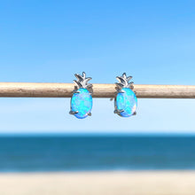 Load image into Gallery viewer, Opal Pineapple Stud Earrings are hanging on a stick in a close-up shot with a beach background blurred.