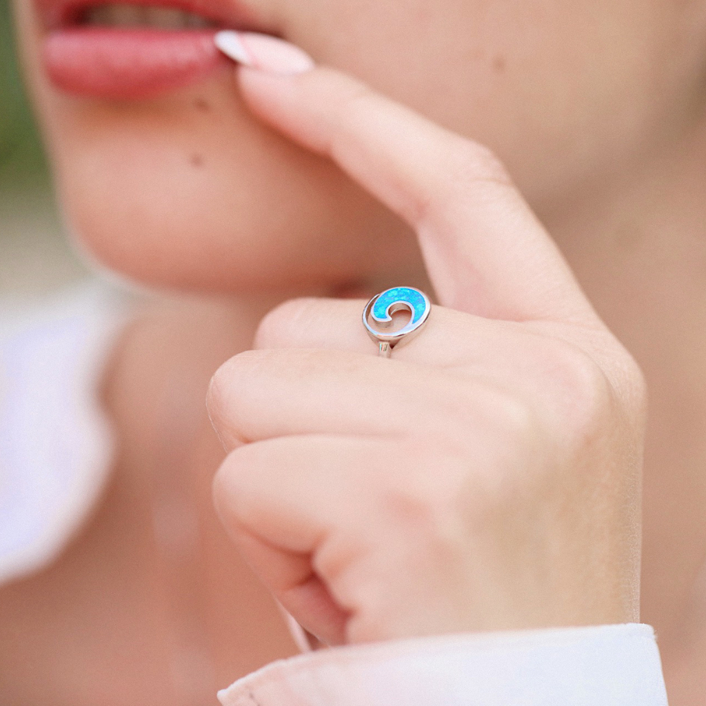 A hand positioned near a woman's lips is displaying the Opal Rip Curl Ring.