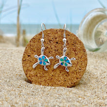 Load image into Gallery viewer, Opal Sea Turtle Flower Earrings displayed on a cork on a sandy beach, perfect for ocean-inspired accessories.