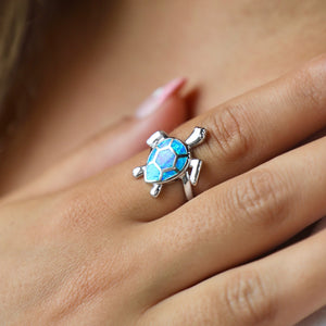 Opal Swimming Sea Turtle Ring displayed closely by being worn on a woman's finger.