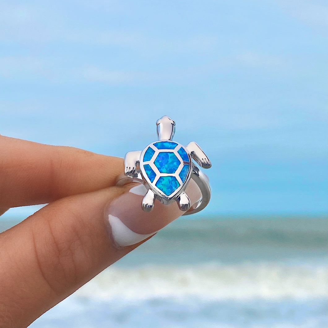 Opal Swimming Sea Turtle Ring displayed closely by being held by a hand.
