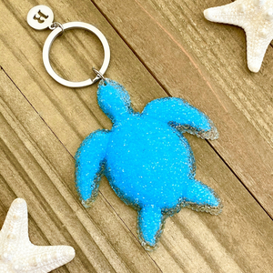 Playful Sea Turtle Keychain displayed on a wooden surface.