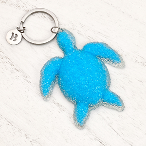 Playful Sea Turtle Keychain displayed on a white wooden surface.