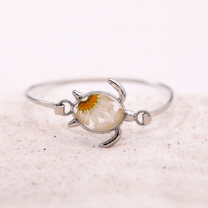 Pressed Daisy Sea Turtle Bracelet displayed on a white fine sand, perfect for beach-themed accessories.