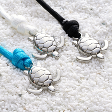 Load image into Gallery viewer, Rope Sea Turtle Bracelets are placed beside each other on a surface full of pebbles.