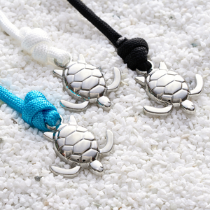 Rope Sea Turtle Bracelets are placed beside each other on a surface full of pebbles.