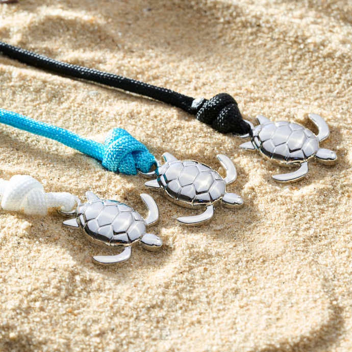 Rope Sea Turtle Bracelets are displayed on a sandy surface.