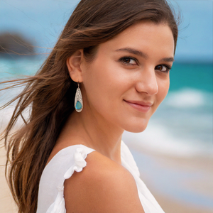 Rustic Sea Glass Drop Earring displayed by being worn on a woman's ear at the beach.