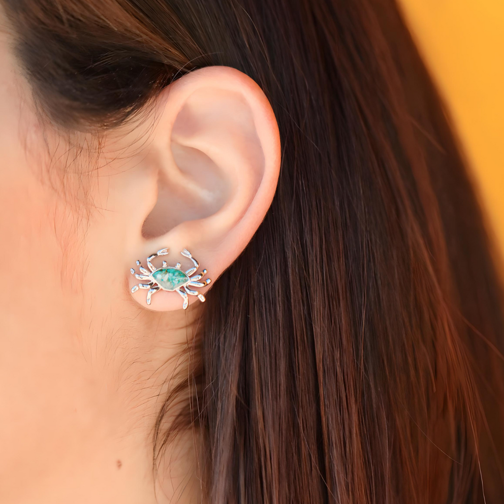 Sand Crab Studs is displayed up close by being worn on a woman's ear.