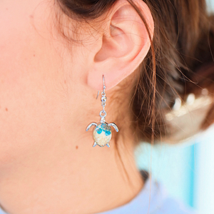 Sand Sea Turtle Earrings displayed up close by being worn.