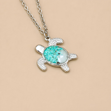 Load image into Gallery viewer, Sand Sea Turtle Necklace displayed on a grain brown surface.