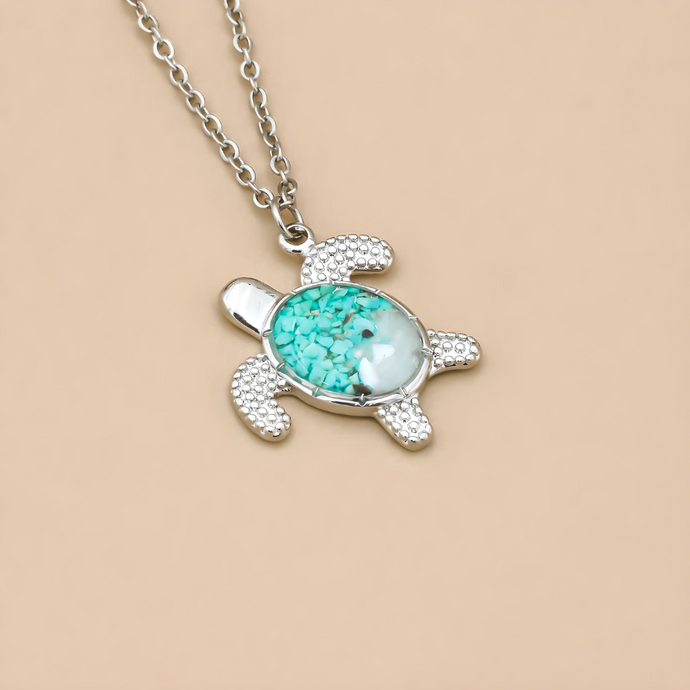 Sand Sea Turtle Necklace displayed on a grain brown surface.