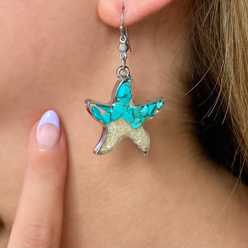 Sand Starfish Earrings in Teal Turquoise displayed closely by being worn on a woman's ear.