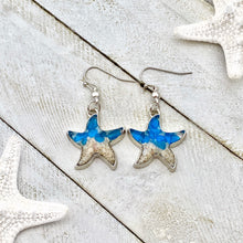 Load image into Gallery viewer, Sand Starfish Earrings in Blue Glass are displayed on a white wooden surface.