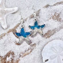 Load image into Gallery viewer, Sand Starfish Earrings in Blue Glass are displayed by being placed on top of a sand covered driftwood.