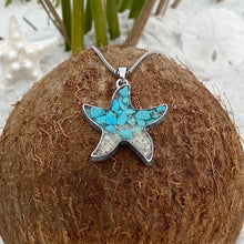 Load image into Gallery viewer, Sand Starfish Necklace in Teal Turquoise is displayed by being placed on top of a dried coconut.