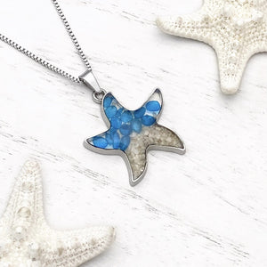 Sand Starfish Necklace in Blue Glass displayed on a white wooden surface.