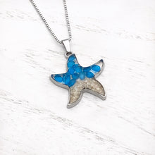 Load image into Gallery viewer, Sand Starfish Necklace in Blue Glass displayed on a white wooden surface.