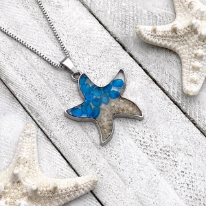 Sand Starfish Necklace in Blue Glass displayed on a white wooden surface
