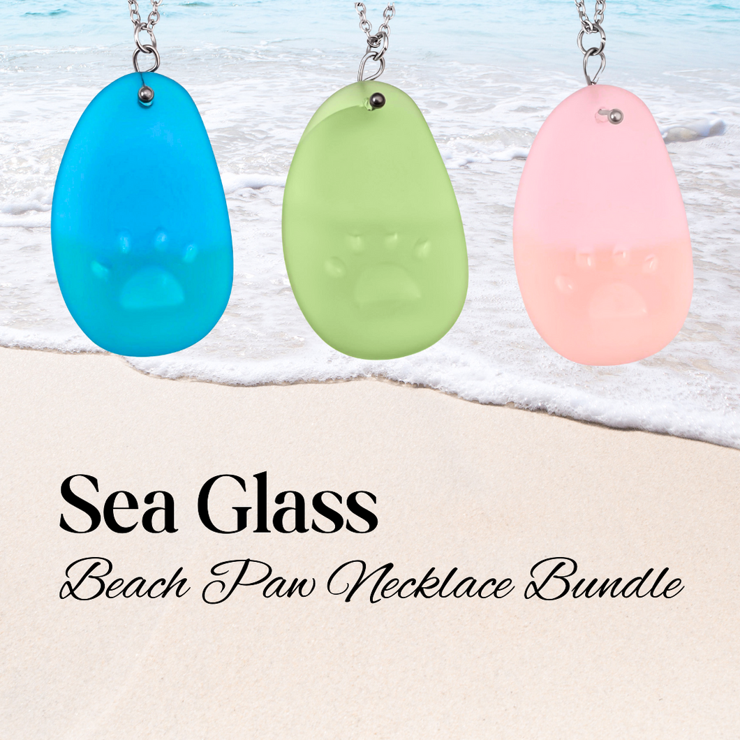 Necklaces being hung up close with a beach background and text that reads 'Sea Glass Beach Paw Necklaces.'