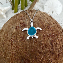 Load image into Gallery viewer, Sea Glass Sea Turtle Necklace in Sky Blue is displayed on top of a dried coconut.