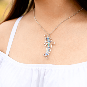 Stacked Sea Glass Dolphin Necklace displayed by being worn around a woman's neck.