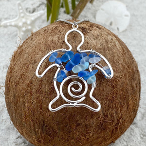 Stacked Sea Glass Sea Turtle Necklace is displayed on top of a dried coconut.