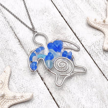 Load image into Gallery viewer, The Stacked Sea Glass Sea Turtle Necklace is displayed on a white wooden surface.