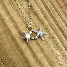 Load image into Gallery viewer, Starfish Hidden Pearl Necklace displayed on a wooden surface.