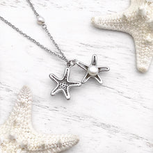 Load image into Gallery viewer, Starfish Hidden Pearl Necklace displayed on a white wooden surface.