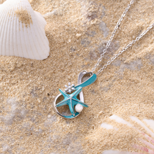 Load image into Gallery viewer, Starfish Pearl Infinity Necklace displayed on a sandy surface with shells around it.