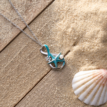 Load image into Gallery viewer, Starfish Pearl Infinity Necklace showcased on a rustic wooden surface covered with sand.