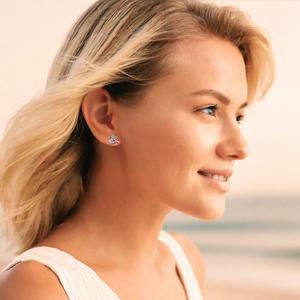 Starfish Shell Studs in Blue is displayed by being worn on a woman's ear at the beach.
