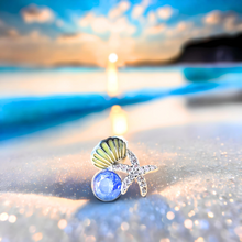 Load image into Gallery viewer, Starfish Shell Stud in Blue is displayed on a glittering sandy shore.