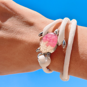 White Rope Sand Sea Turtle Bracelet with Pink Pebbles is displayed by being worn around a woman's wrist.
