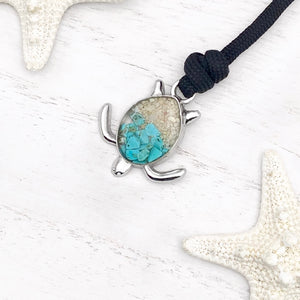 Black Rope Sand Sea Turtle Bracelet in Teal Turquoise is displayed on a white wooden surface.