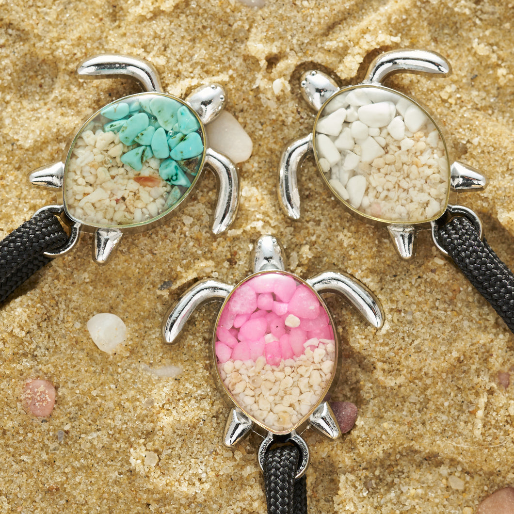 Black Rope Sand Sea Turtle Bracelets are all placed on a sandy surface.