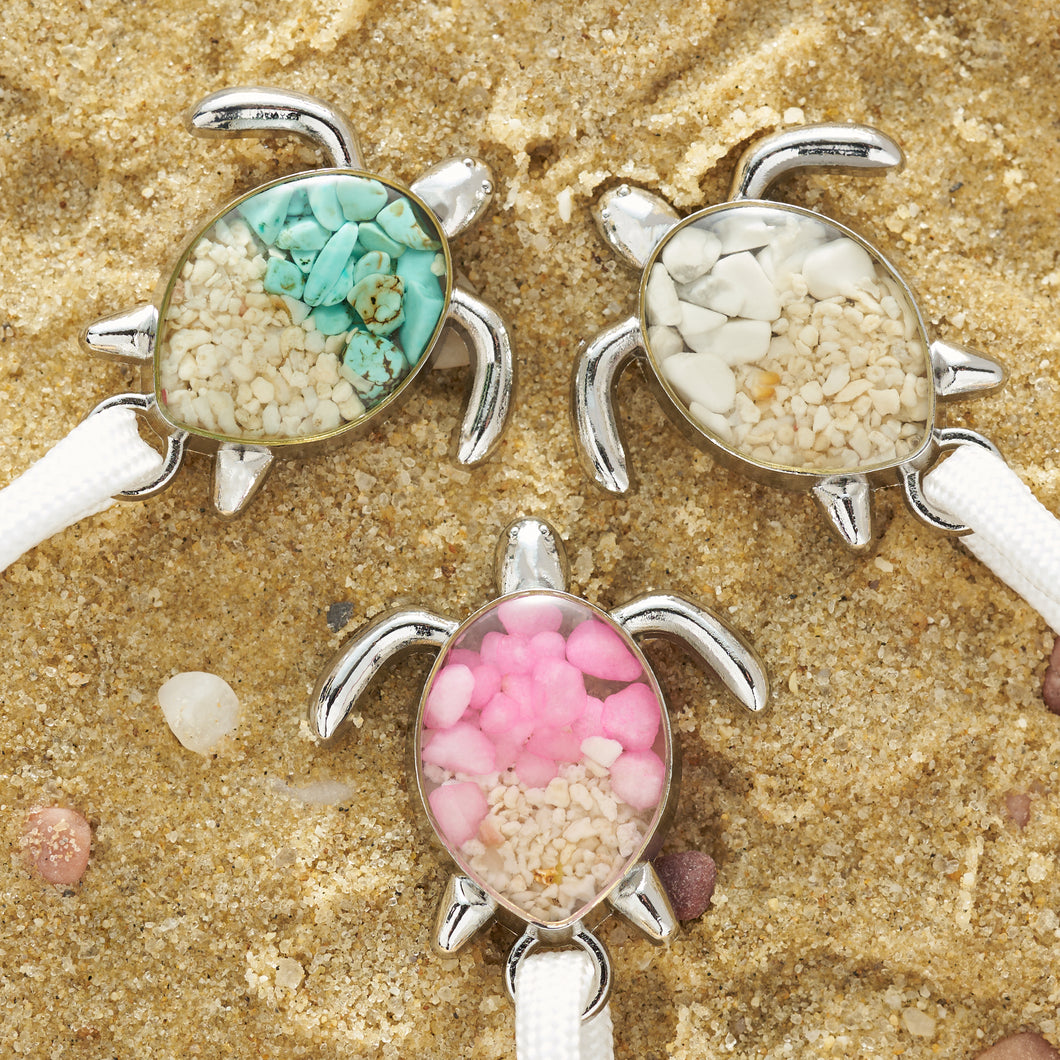White Rope Sand Sea Turtle Bracelets are all placed on a sandy surface.