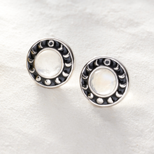 Load image into Gallery viewer, Moonstone Moon Phase Studs resting on fine sand.