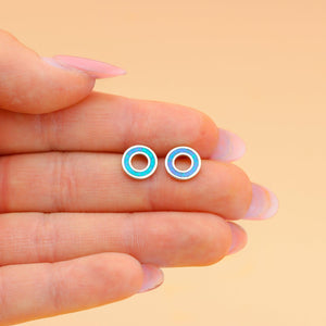 Opal Floatie Studs are displayed by placing them on a woman's palm, nestled between her two fingers.