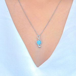 Opal Music Note Necklace displayed closely by being worn around a woman's neck.