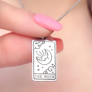 The Moon Tarot Card Necklace displayed closely by being held by a woman's finger.
