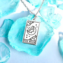 Load image into Gallery viewer, The Moon Tarot Card Necklace displayed on a blue crystal surrounded by other blue crystals.