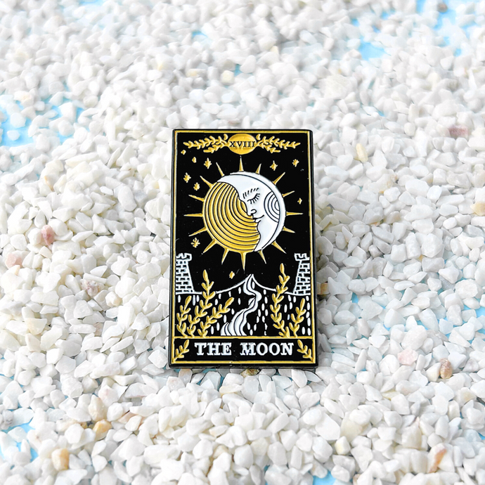 The Moon Tarot Card Pin displayed on sandy terrain.