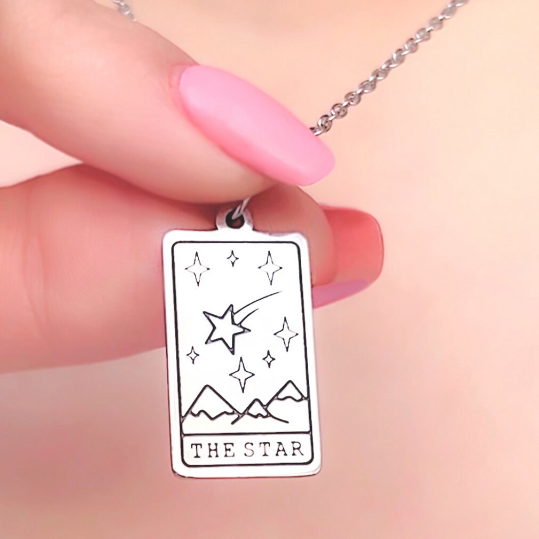 The Star Tarot Card Necklace displayed closely by being held by a woman's finger.