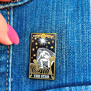 The Star Tarot Card Pin displayed on denim cloth.