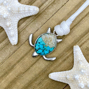 White Rope Sand Sea Turtle Bracelet in Teal Turquoise is displayed on a wooden surface.