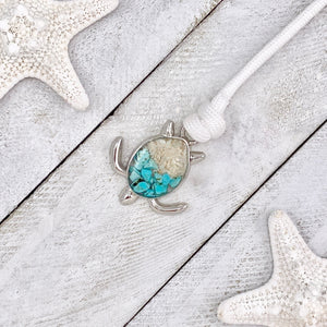 White Rope Sand Sea Turtle Bracelet in Teal Turquoise is displayed on a white wooden surface.